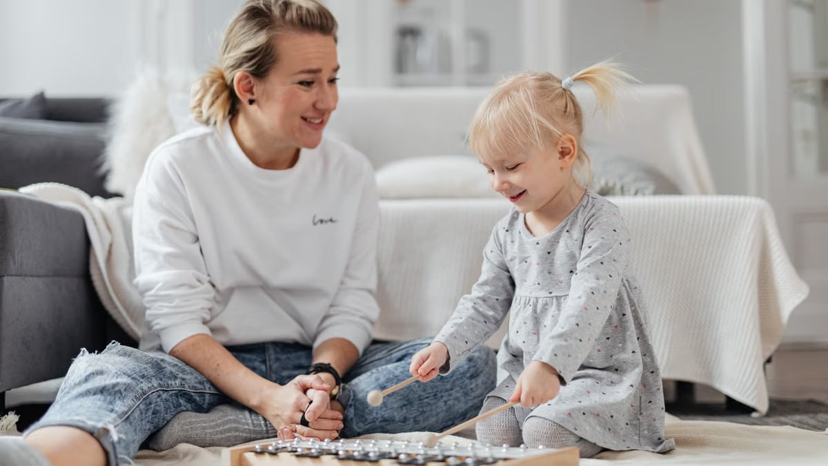 Smiling mother and child playing xylophone together in cozy home setting.